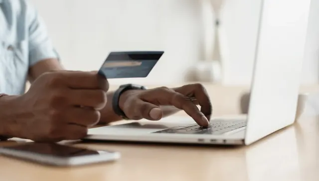 Person shopping online with a laptop and payment card